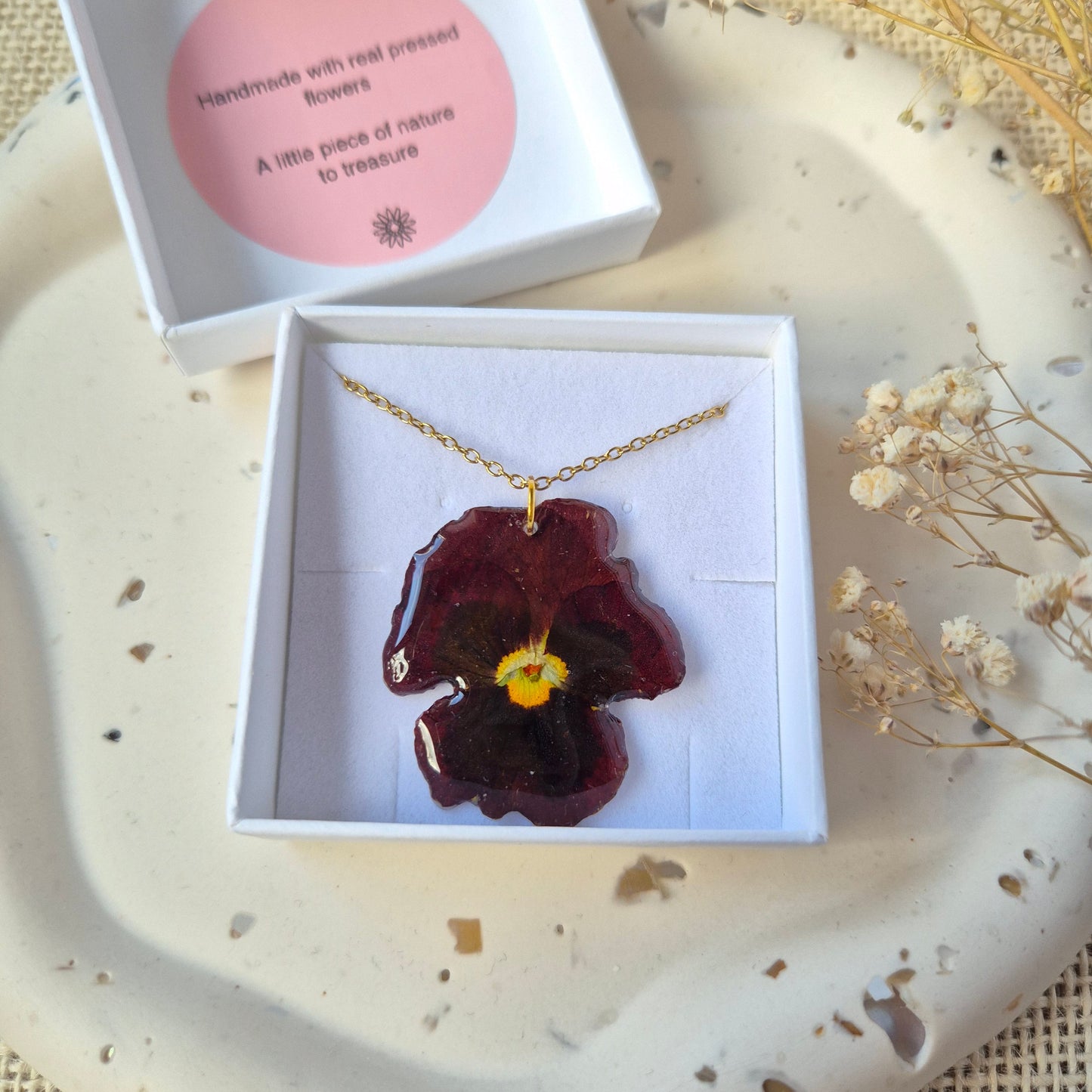 Necklace with a real pressed pansy pendant. Shown in a Blossom and tide gift box.