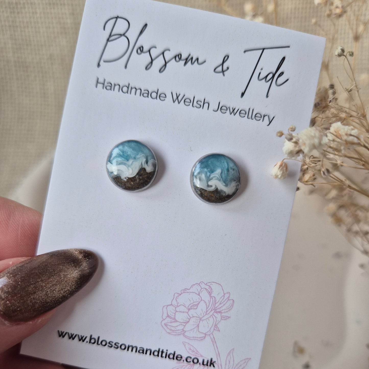 A close up view of a pair of welsh beach sand earrings shown on a blossom & tide branded card.