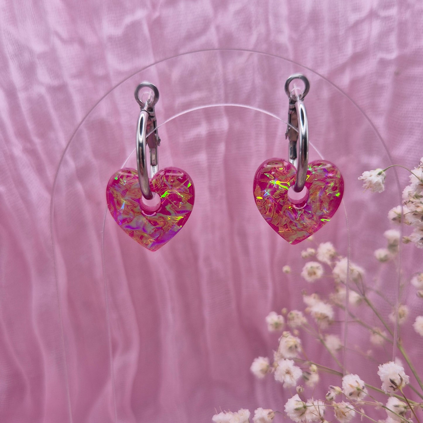 Handmade resin heart earrings with shimmering pink dichroic film.