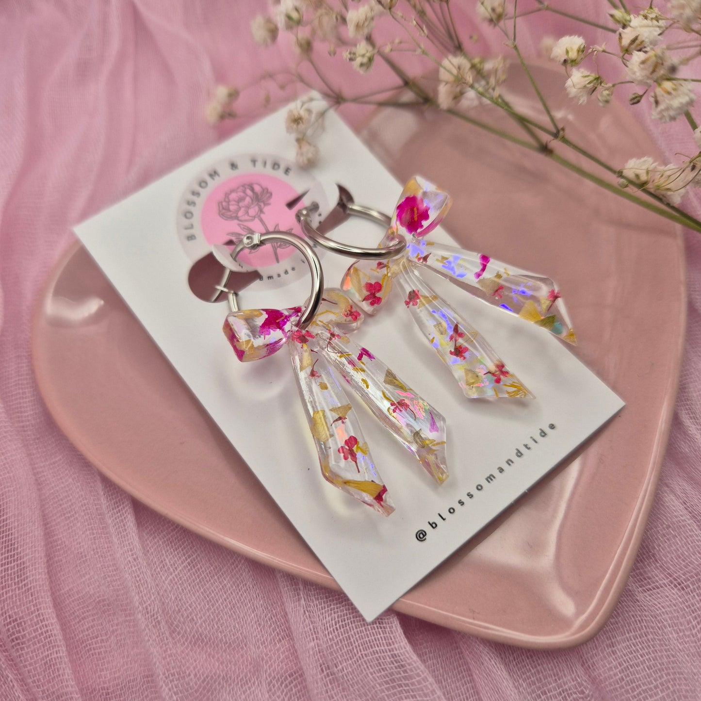 Handmade resin bow hoop earrings with real pink and yellow flower petals and shimmering mylar flakes.
