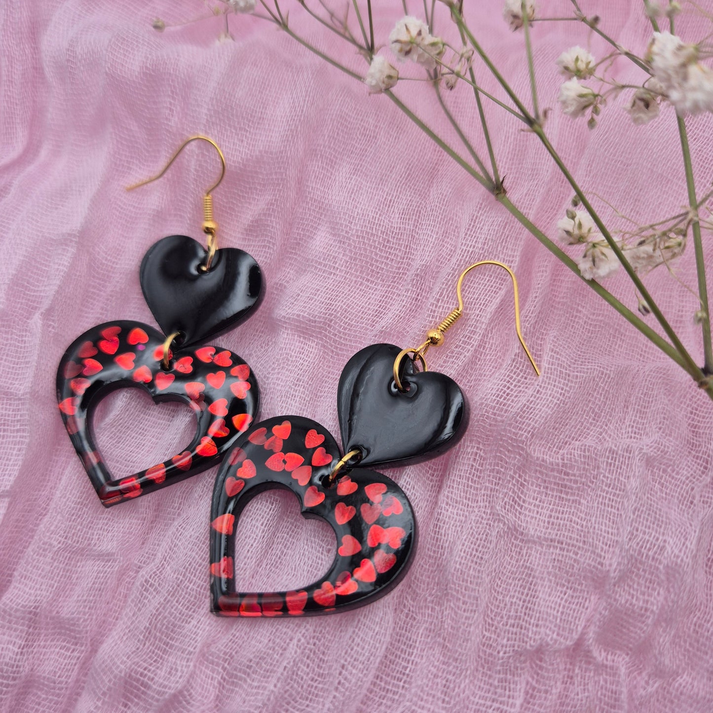 Handmade resin heart earrings featuring red glitter and plain black hearts.
