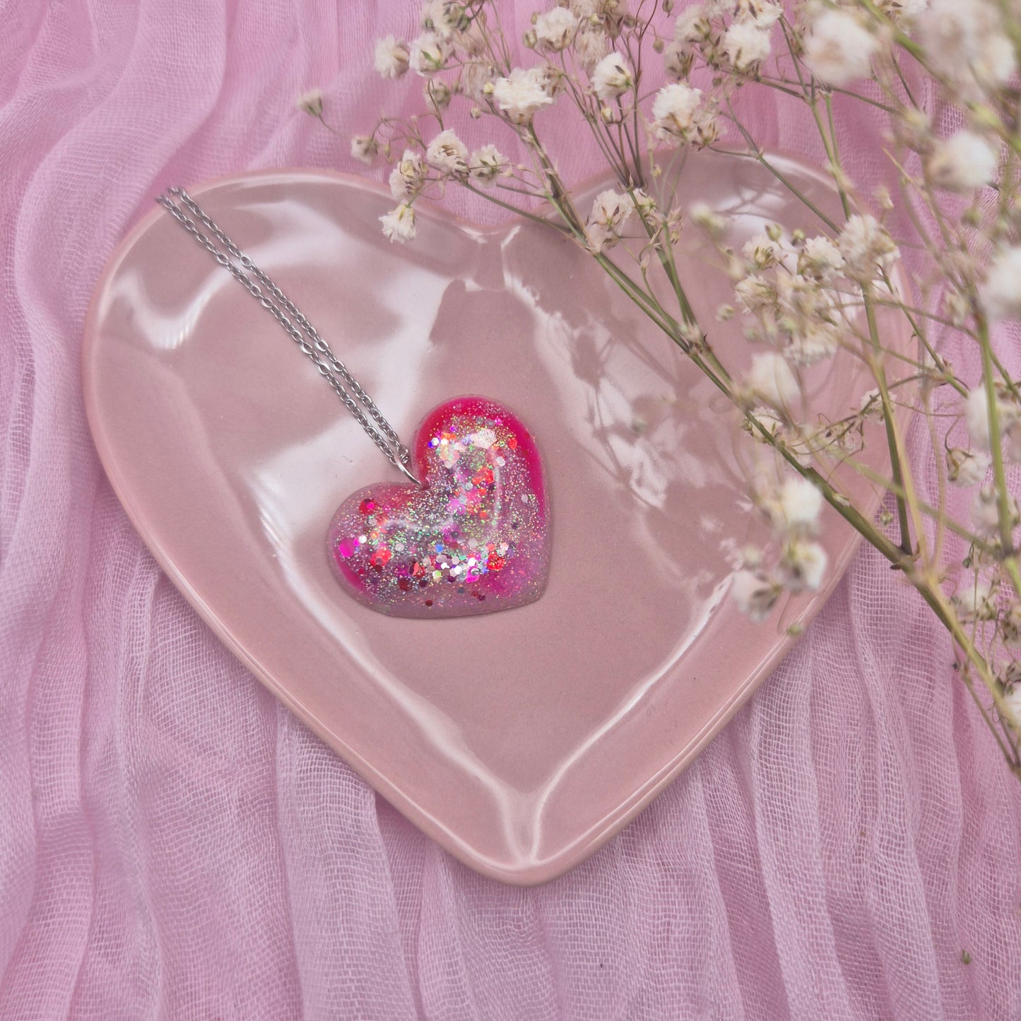 Heart-shaped resin necklace with red, pink, and glitter accents.