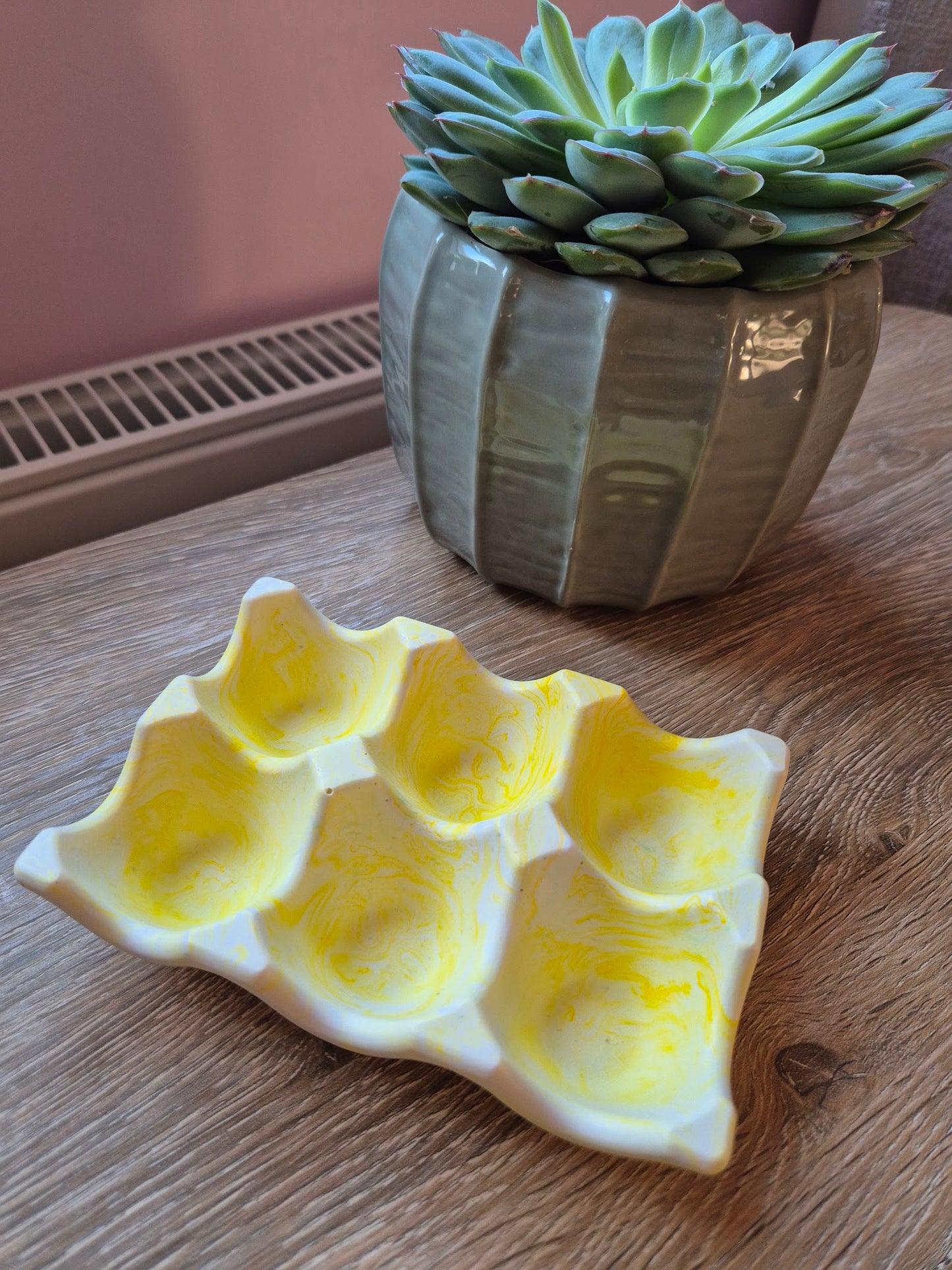 Yellow marble egg tray on a wood table with a plant in the background