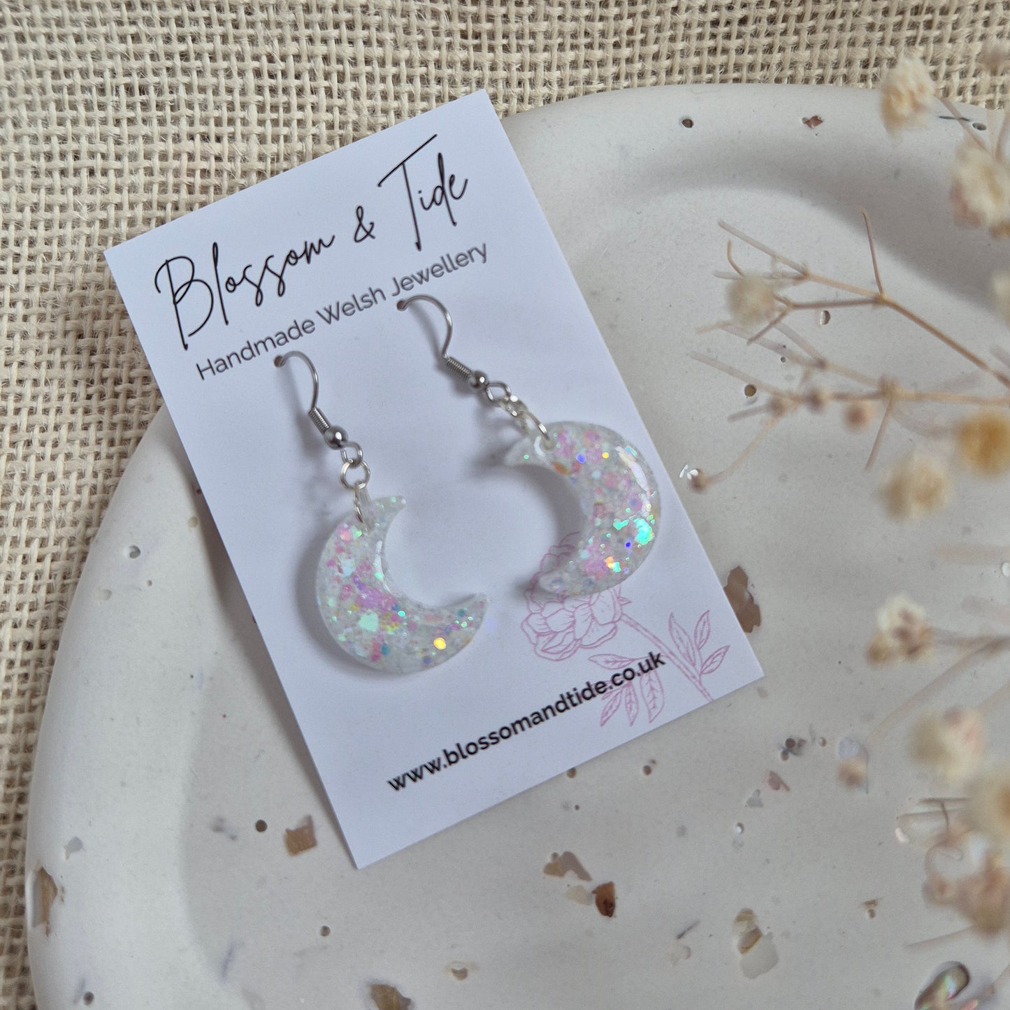 Half moon shaped glitter earrings with opalescent shimmer on silver hooks.