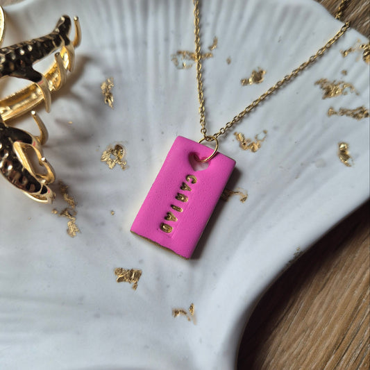 Pink Welsh love necklace displayed on a gold chain, handmade in Wales
