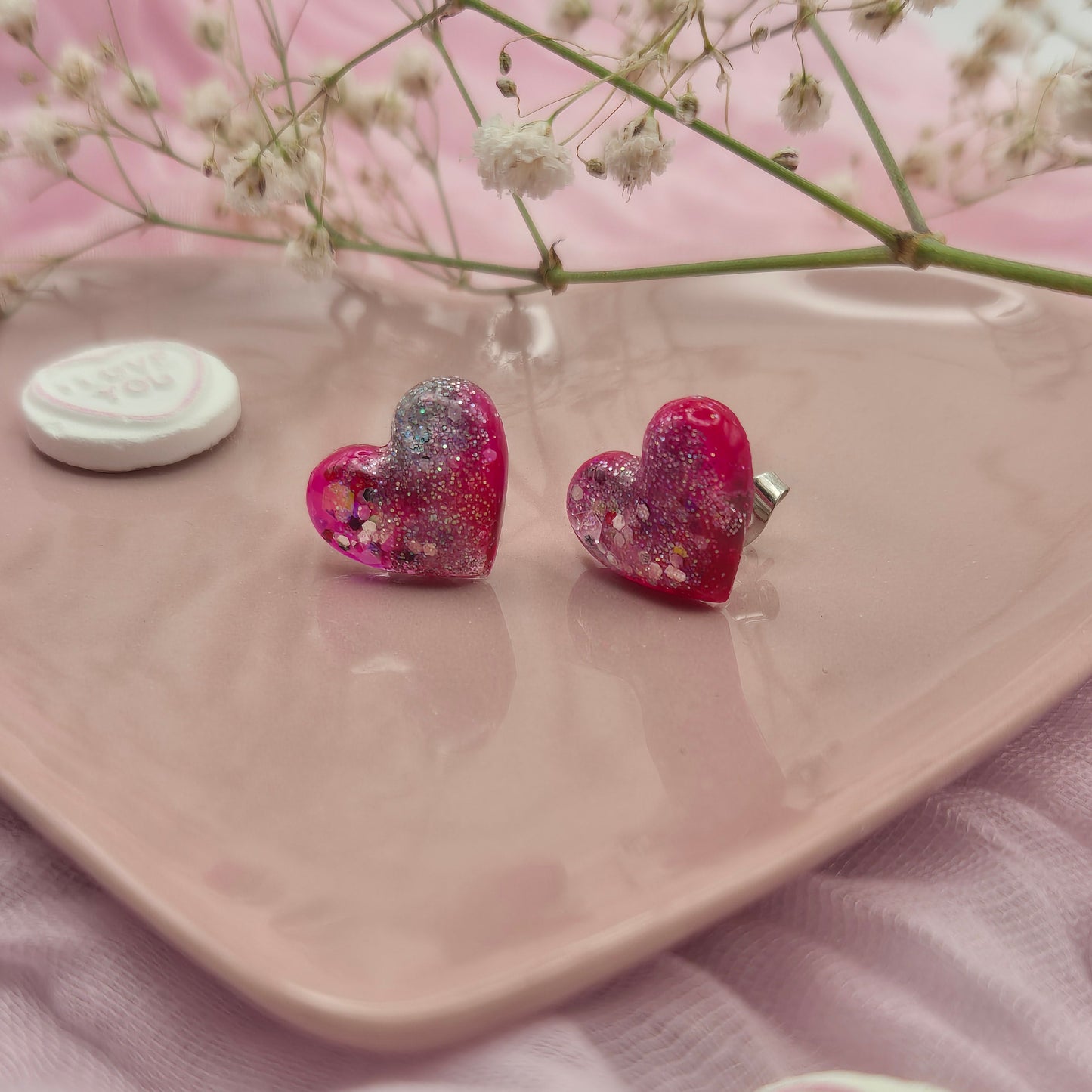 Sparkling red and pink heart earrings with glitter highlights.