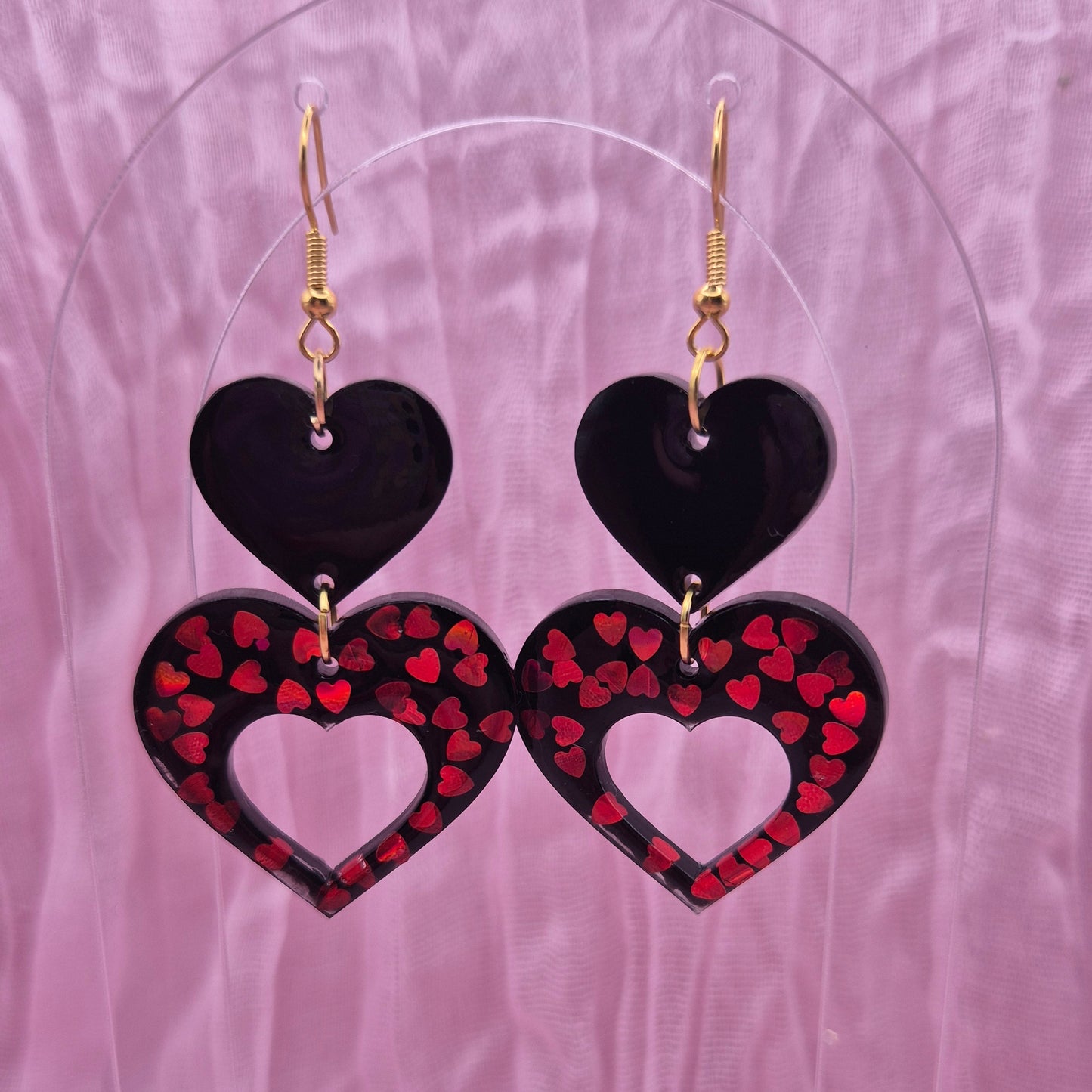 Two-tiered heart earrings with red glitter hearts and black resin.