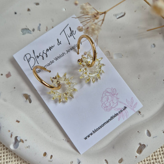 Sun earrings filled with a mix of yellow and white pressed flowers on a stainless steel gold hoop. Presented on a Blossom & Tide branded card.