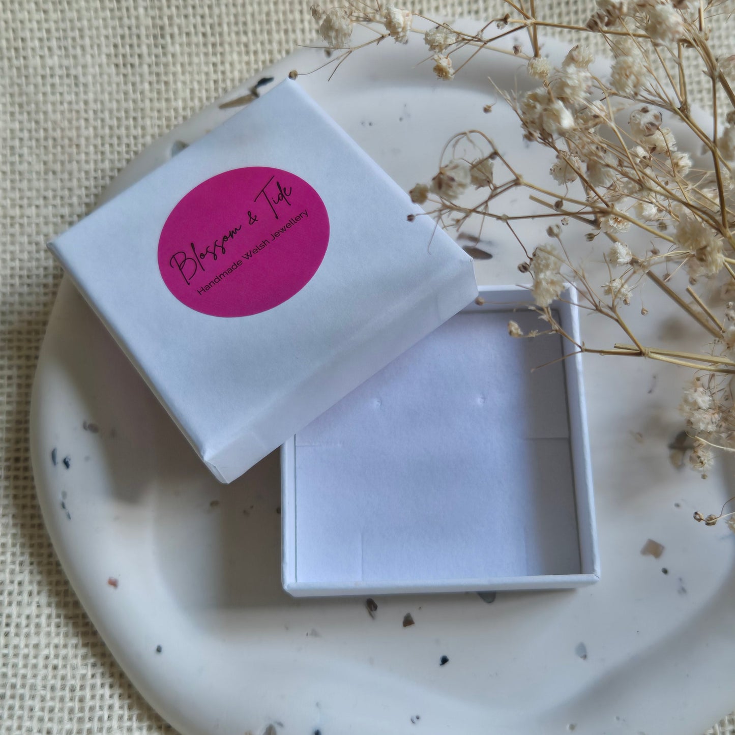 white blossom and tide branded jewellery box open on a neutral tray and background