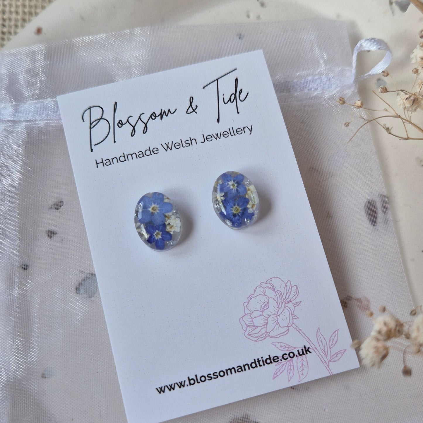 Pair of floral earrings on a 'Blossom & Tide' branded card.