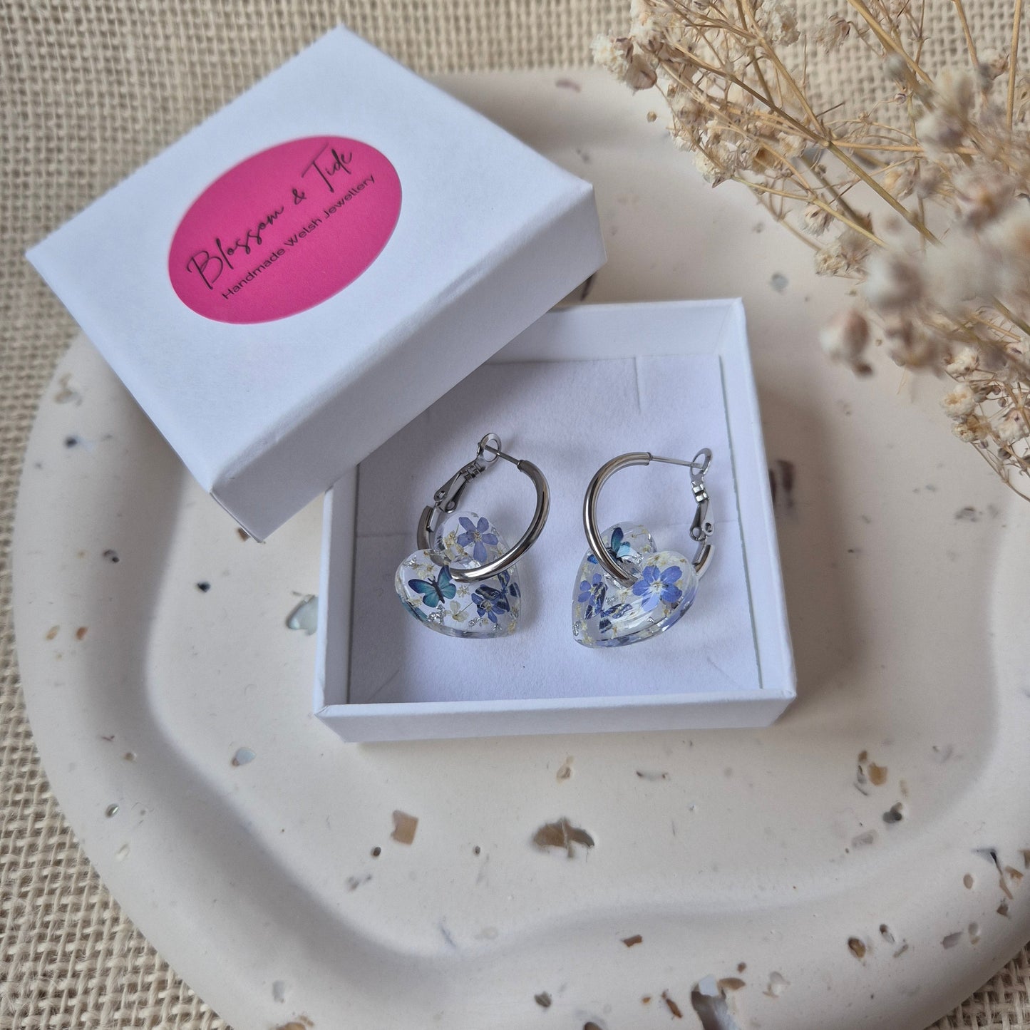 Earrings in a box on a decorative plate with a pink card