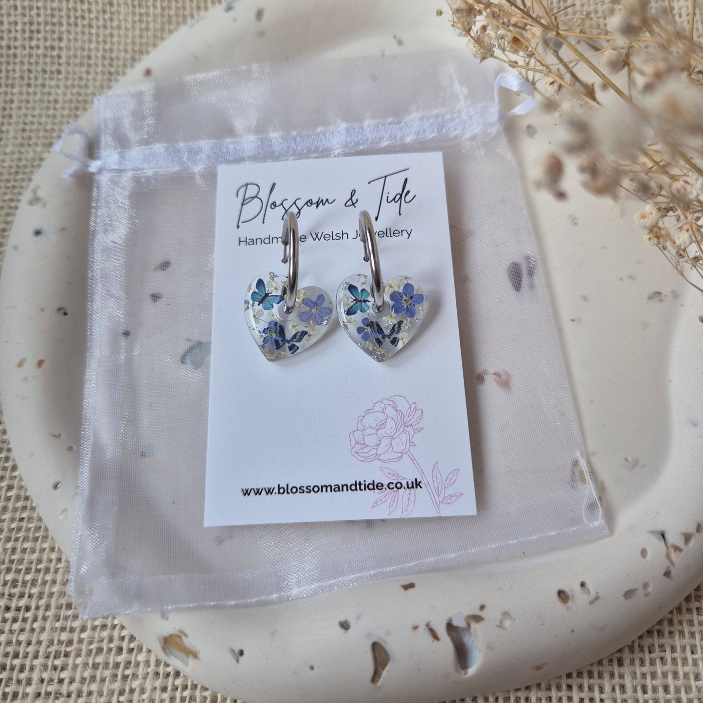 Pair of floral earrings on a branded card on a decorative plate