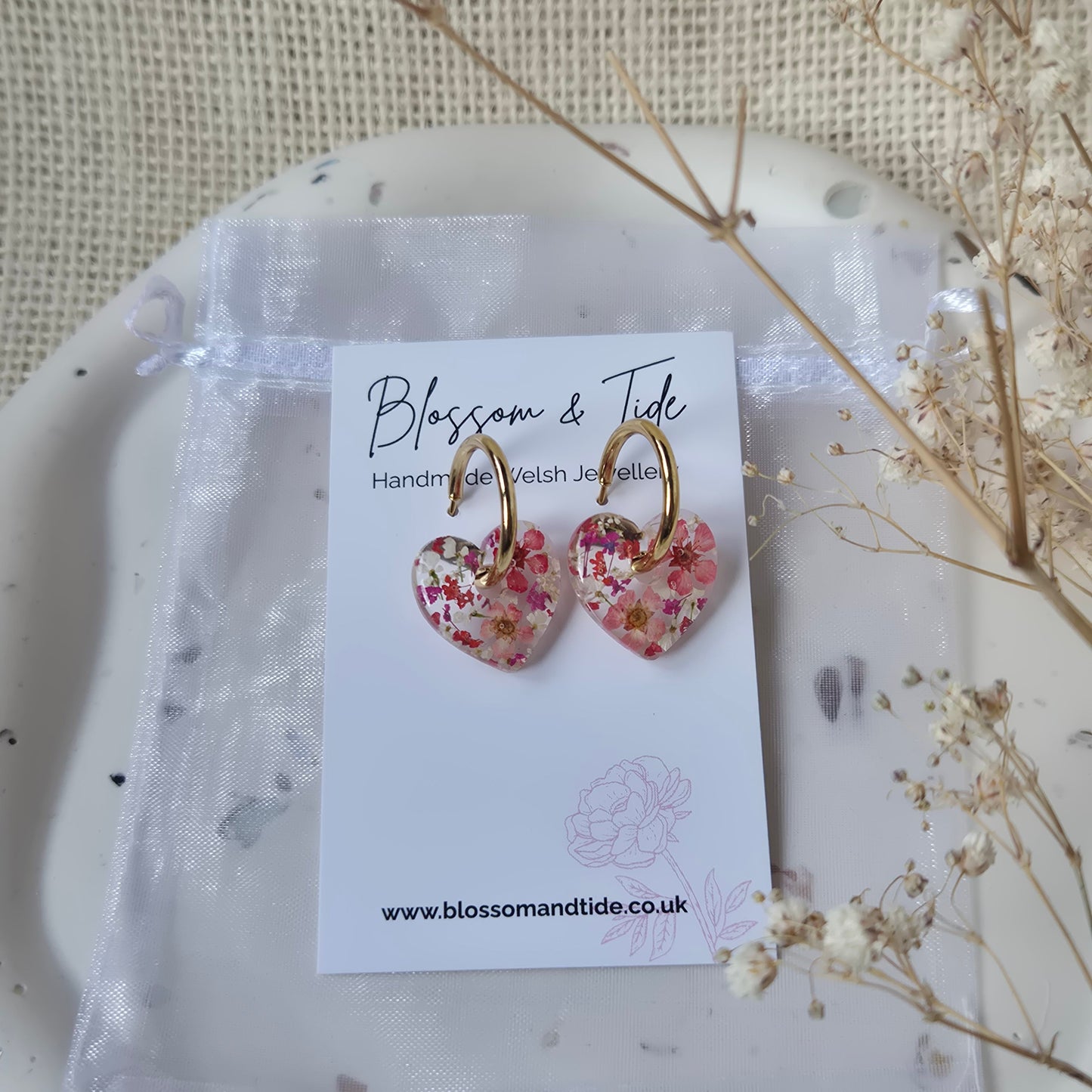 Floral earrings on a branded card with a natural background
