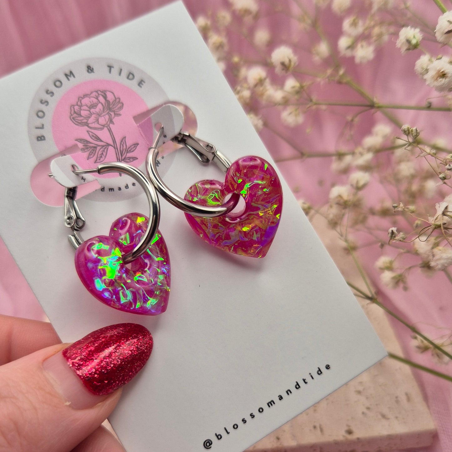 Handmade resin heart earrings with shimmering pink dichroic film.
