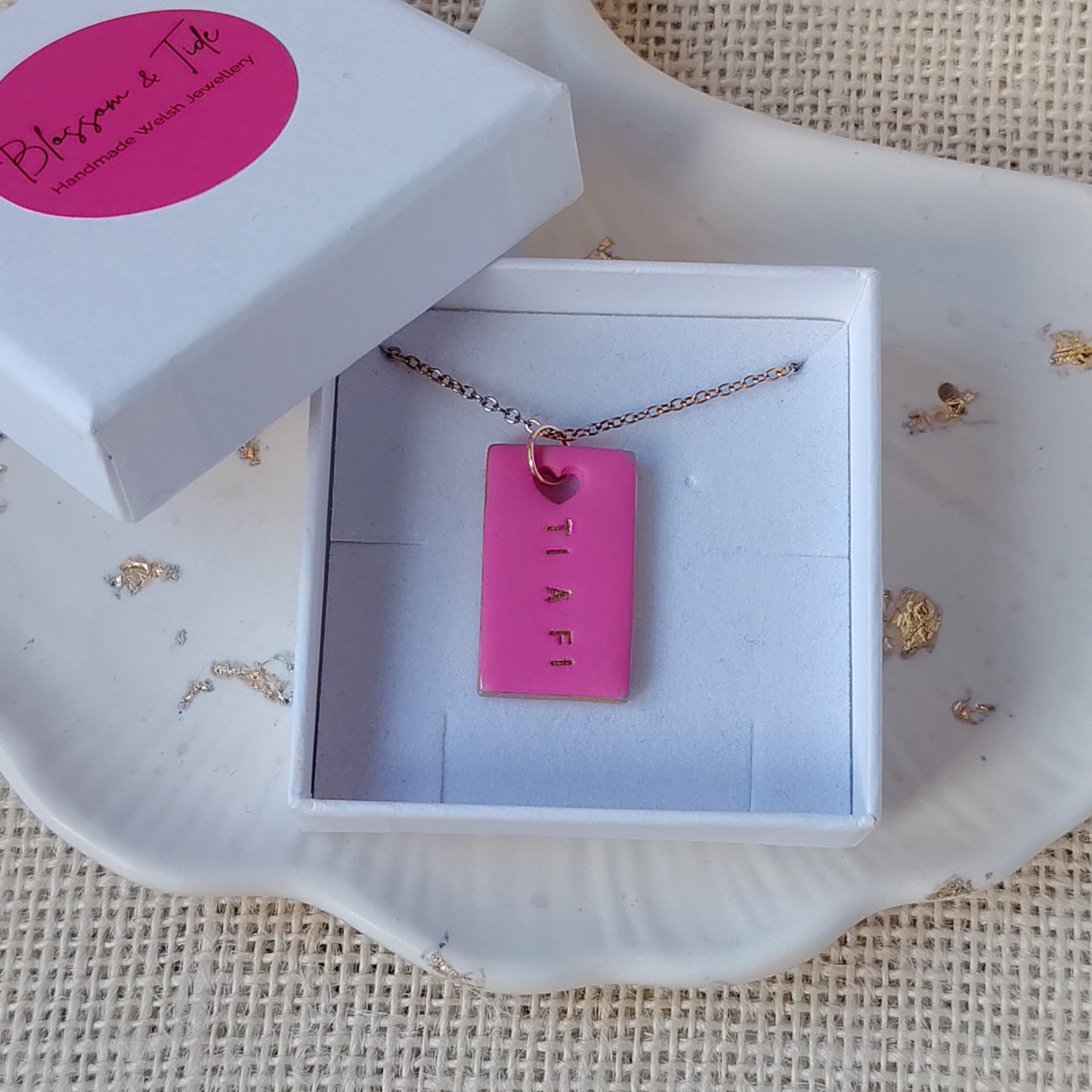 Pink necklace in an open jewelry box on a textured surface