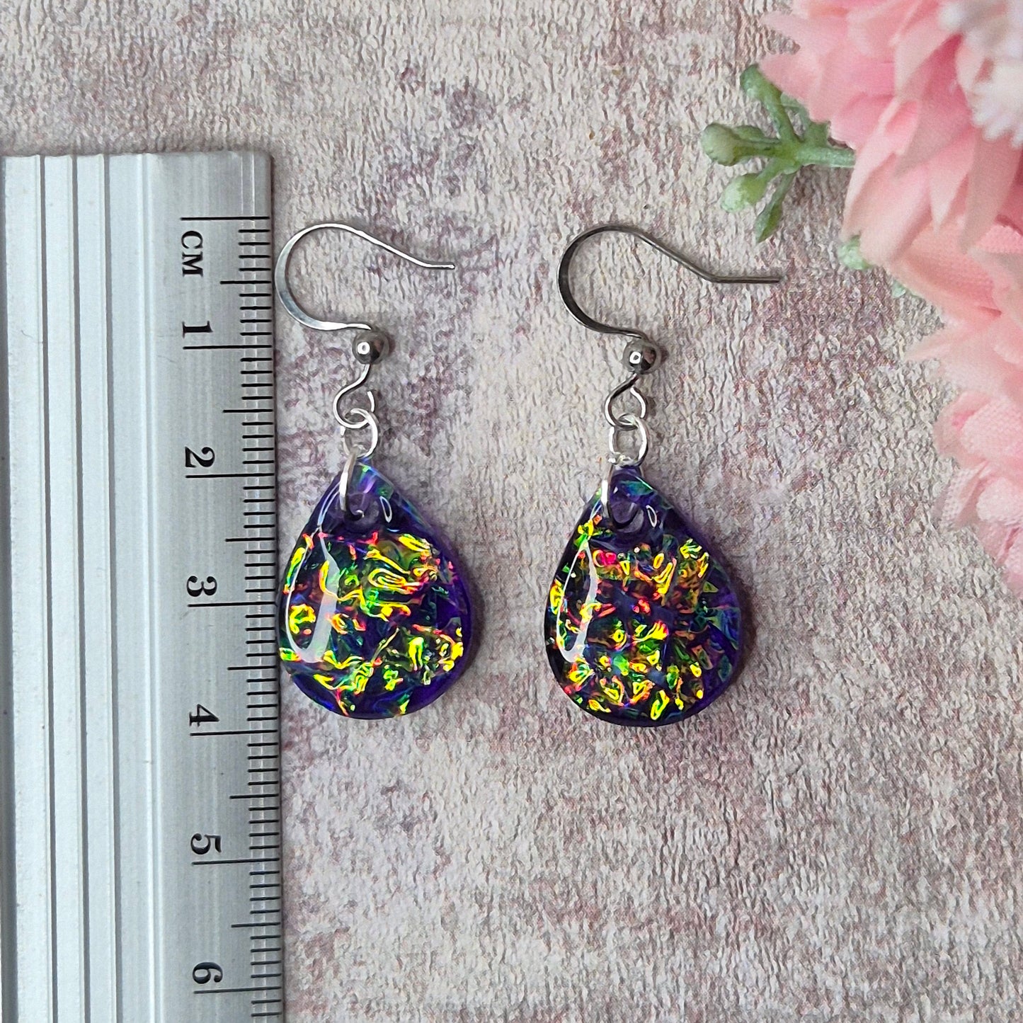 Teardrop shape purple dichroic resin earrings with a ruler as scale reference