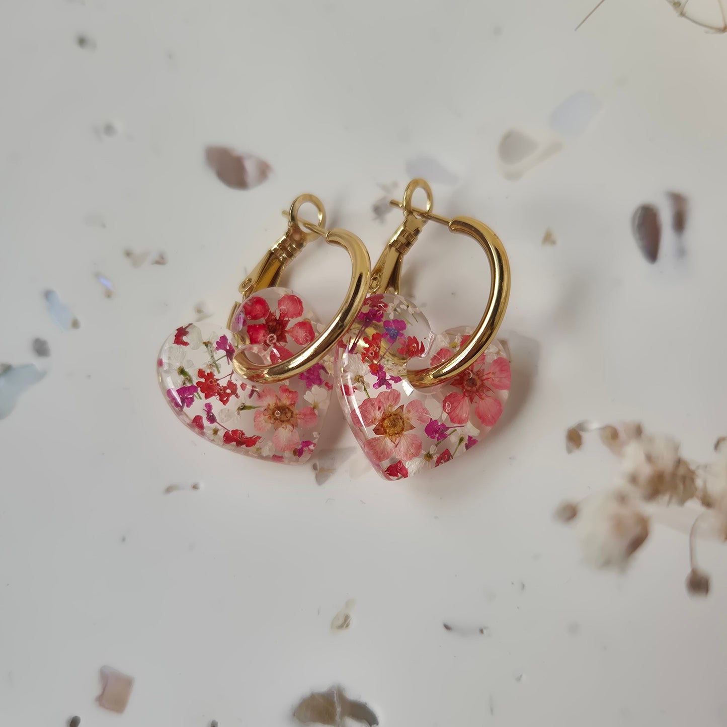 Pair of floral earrings with gold hoops on a light background