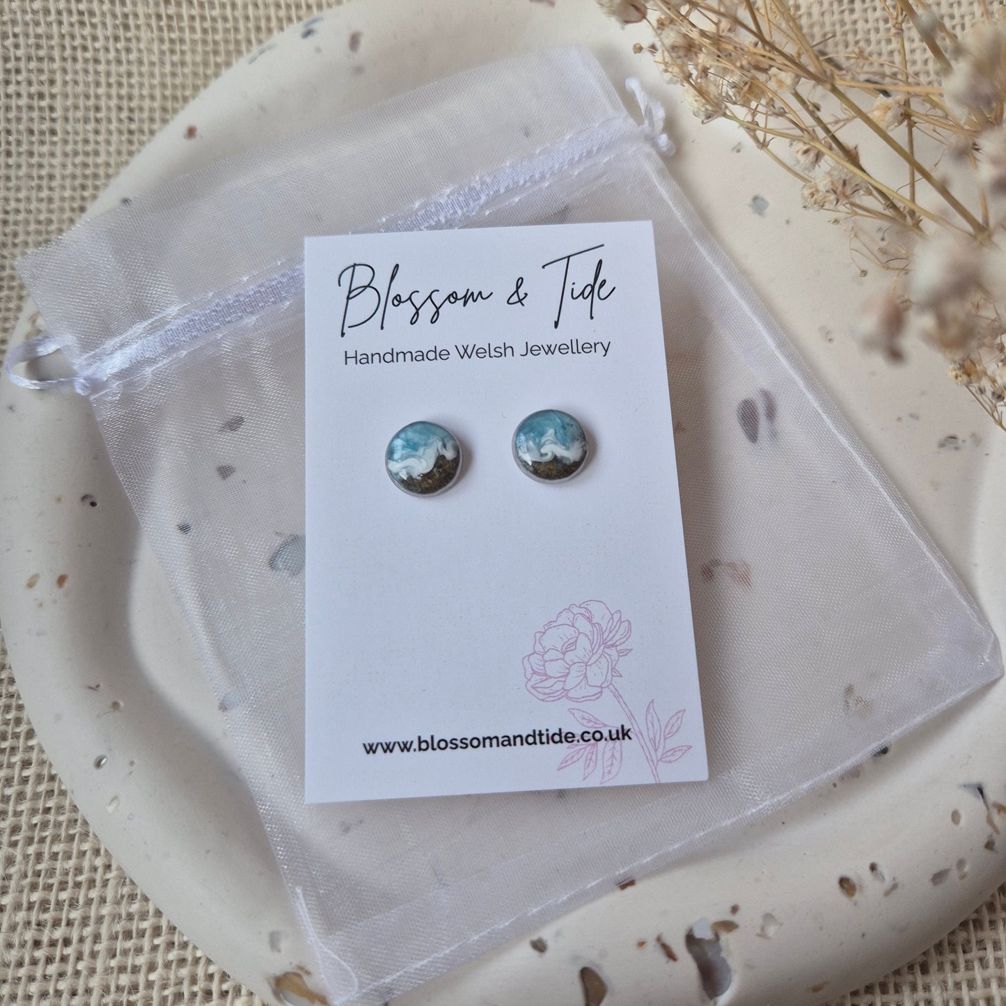A pair of welsh beach sand earrings shown on a blossom & tide branded card. With organza bag packaging.