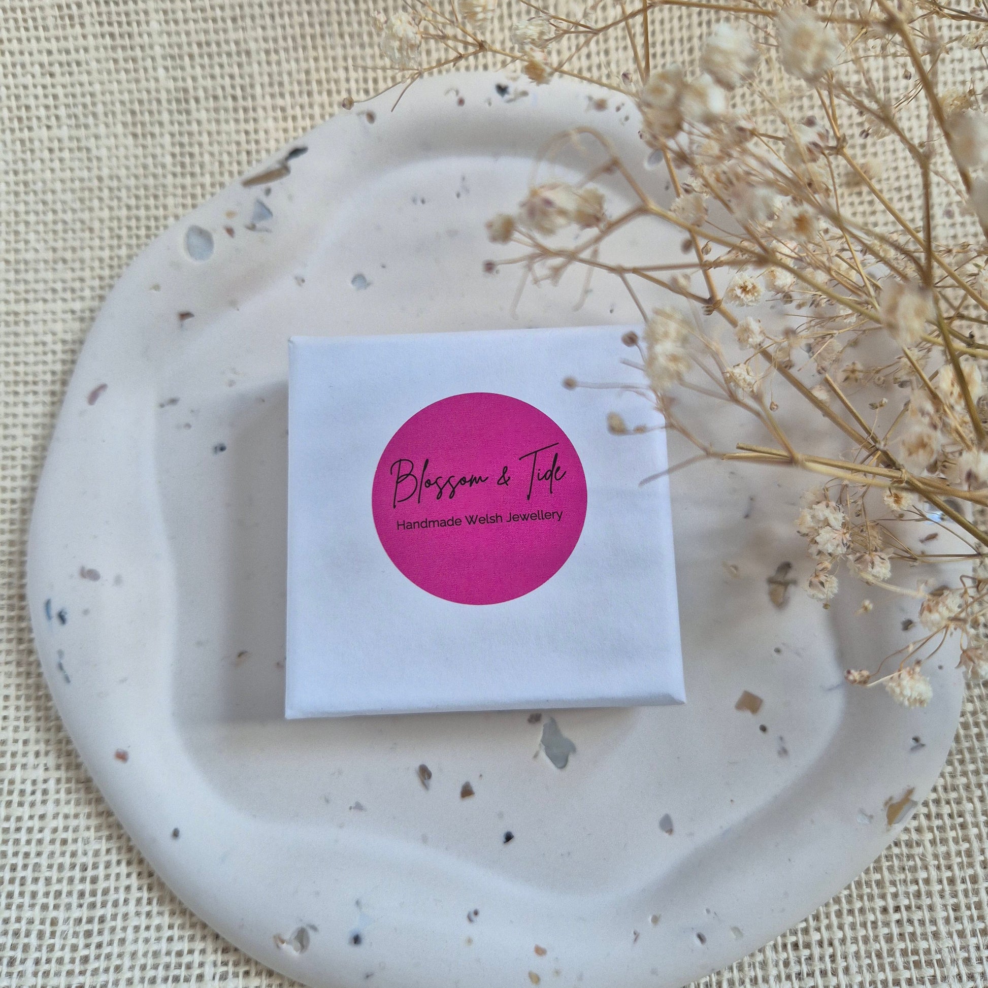 white blossom and tide branded jewellery box on a neutral tray and background