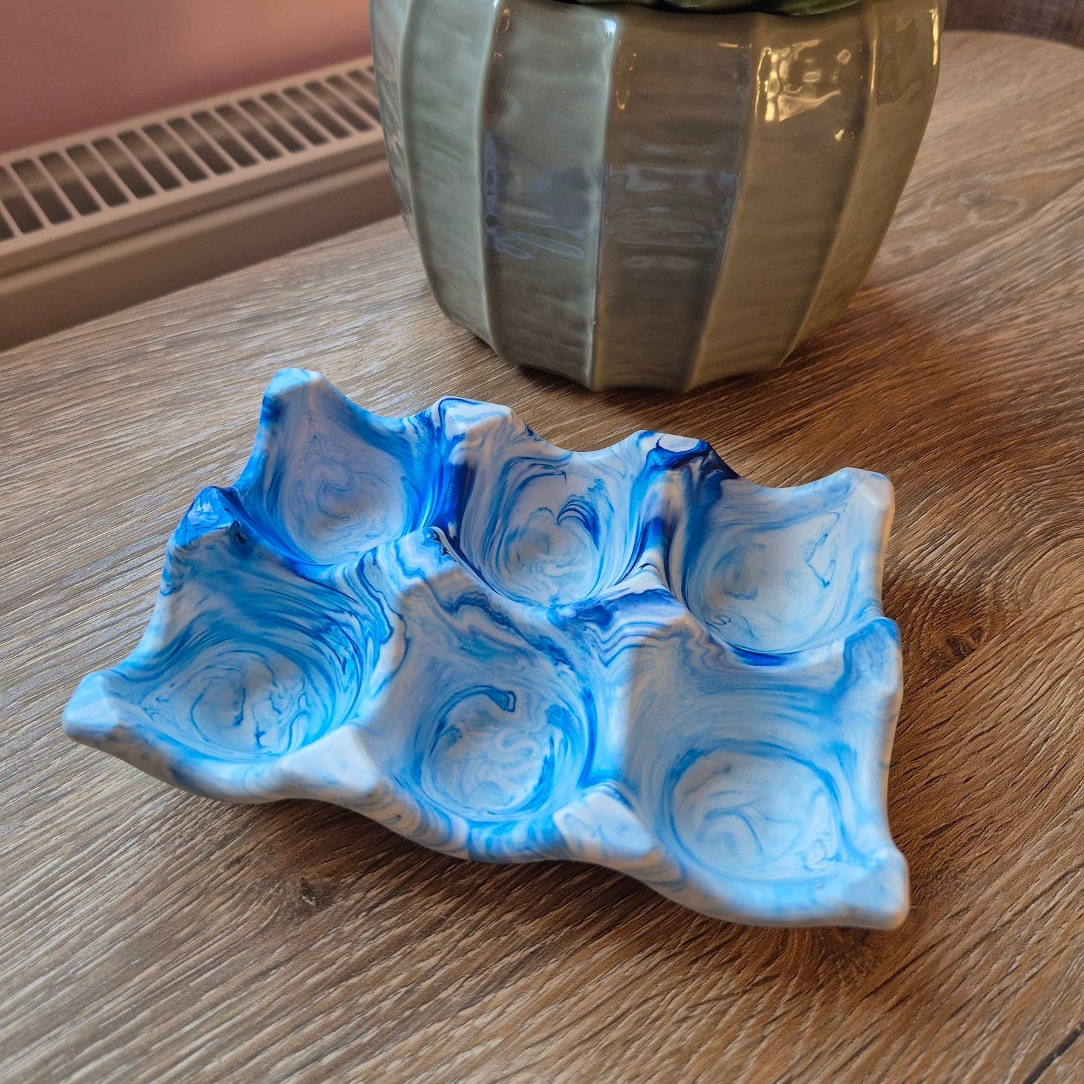 Blue marble egg tray on a wood table with a plant in the background