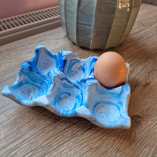 Blue marble egg tray on a wood table with a plant in the background