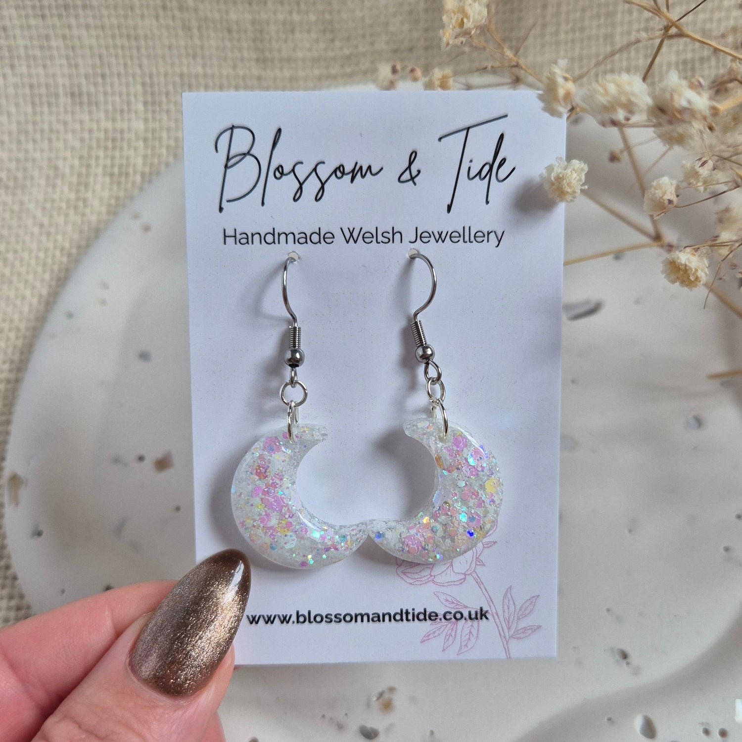 Opal shimmer half moon earrings displayed on branded card.