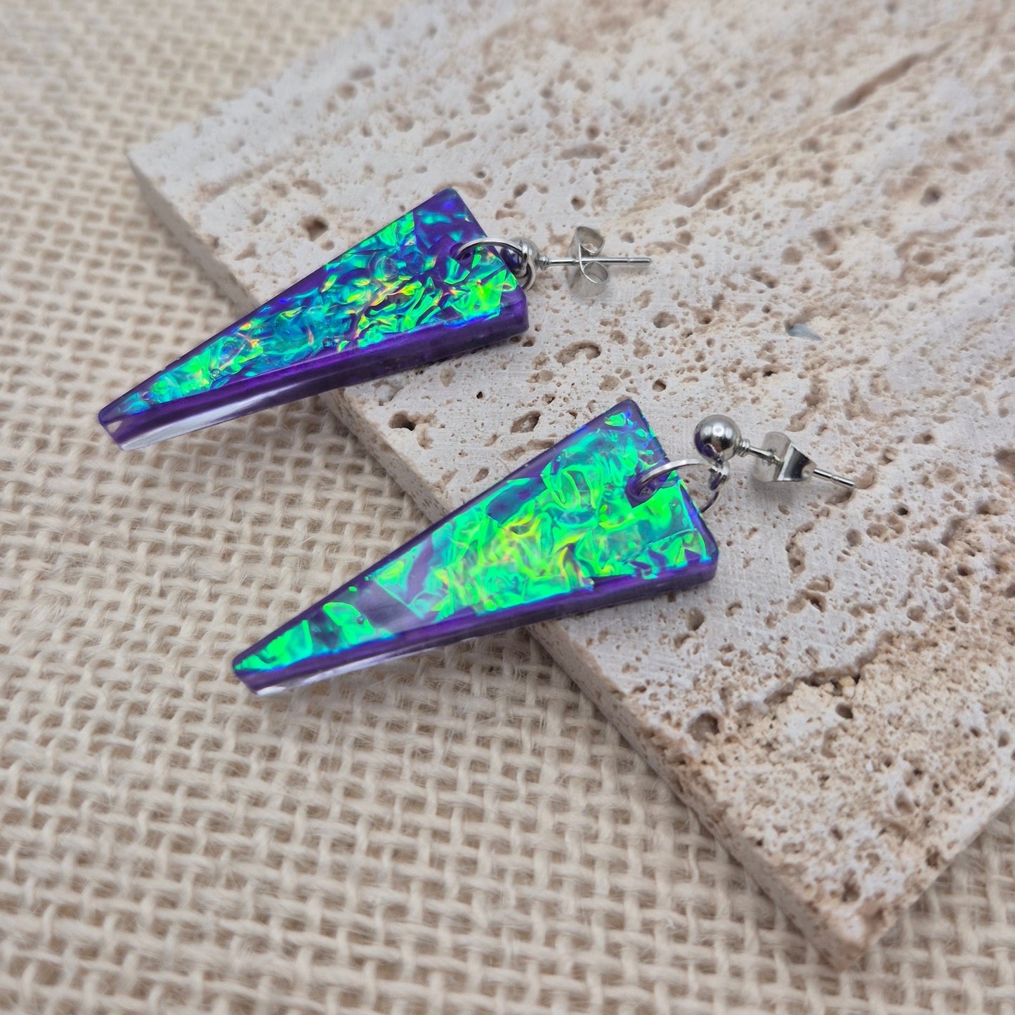 Close-up of geometric resin earrings with a dichroic glass effect, on hypoallergenic stud posts