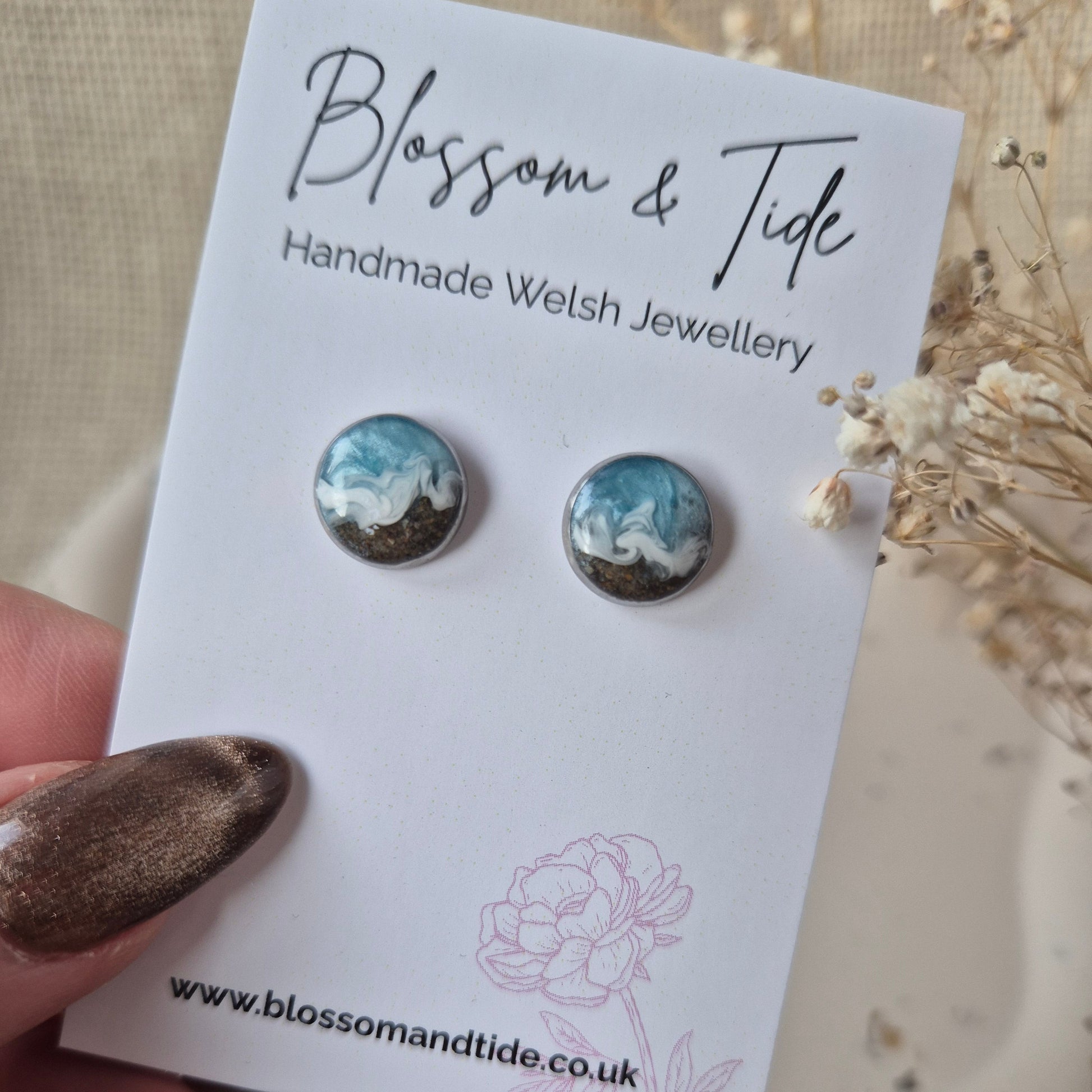 A close up view of a pair of welsh beach sand earrings shown on a blossom & tide branded card.