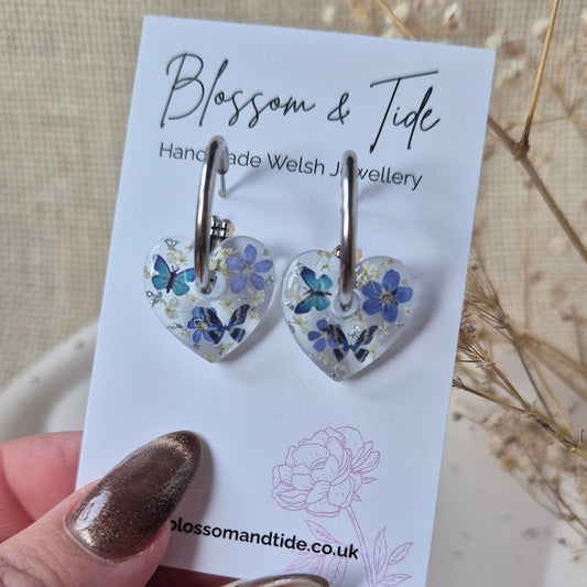 Handmade Welsh jewelry earrings on a branded card held by a hand with gold nail polish.
