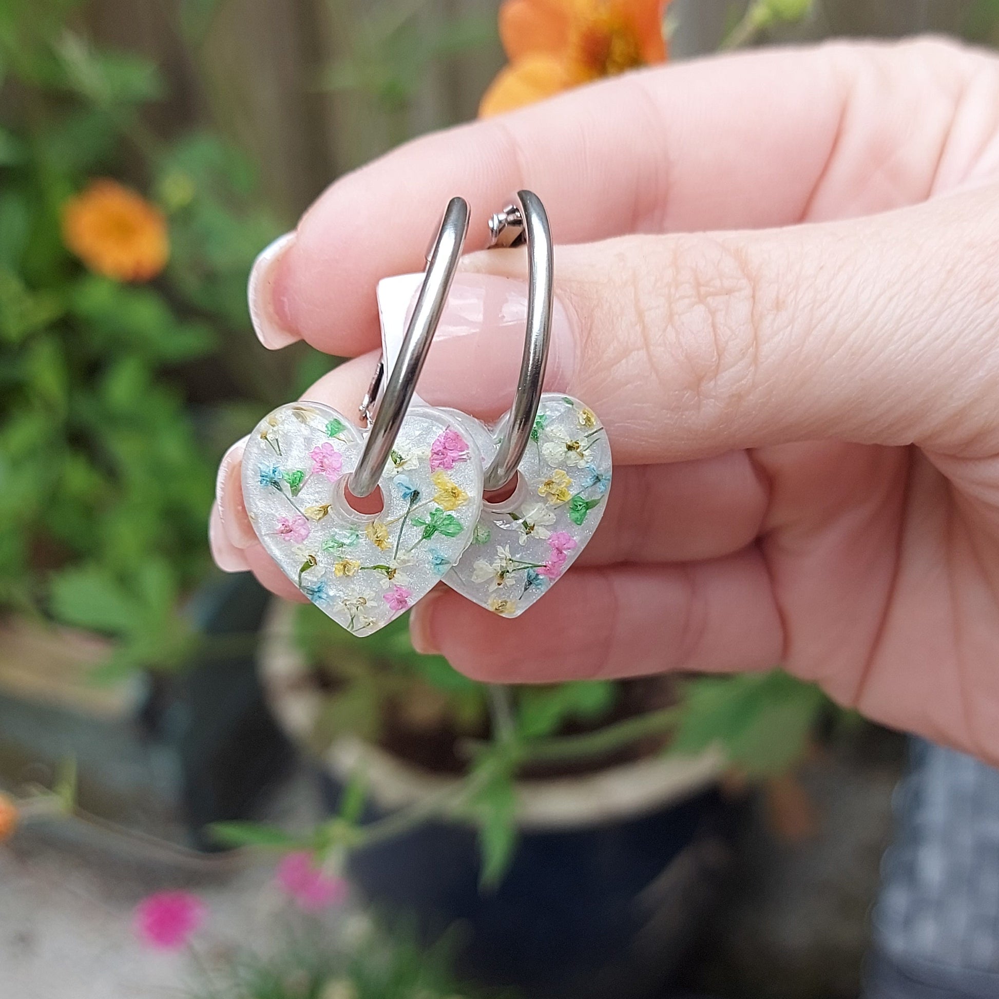 Heart-shaped hoop earrings with multicoloured flowers on a pearly background