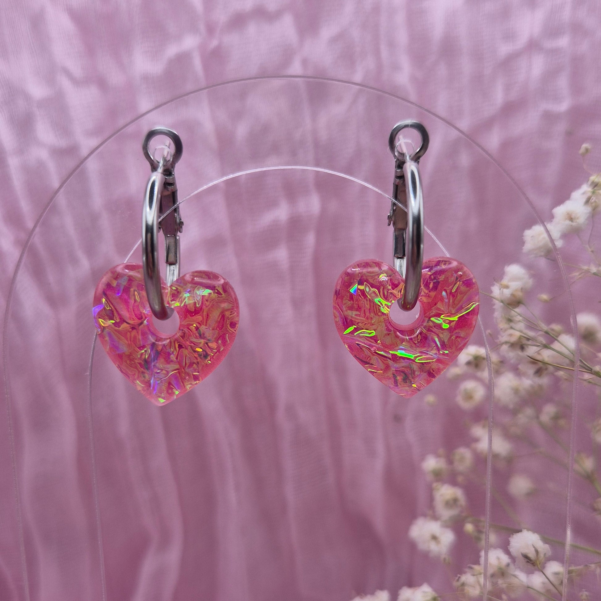 Handmade resin heart earrings with shimmering pink dichroic film.