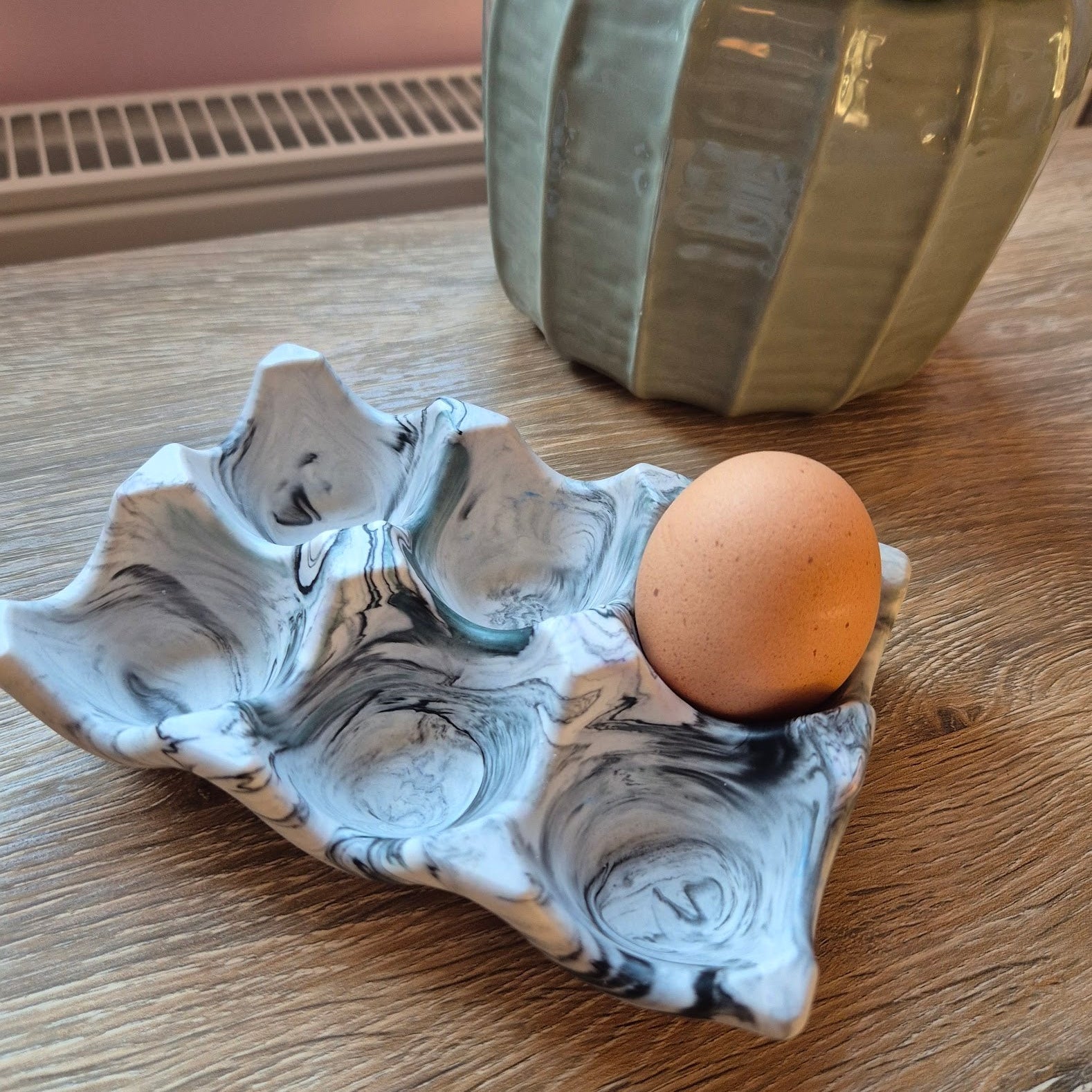 Black marble egg tray on a wood table with a plant in the background