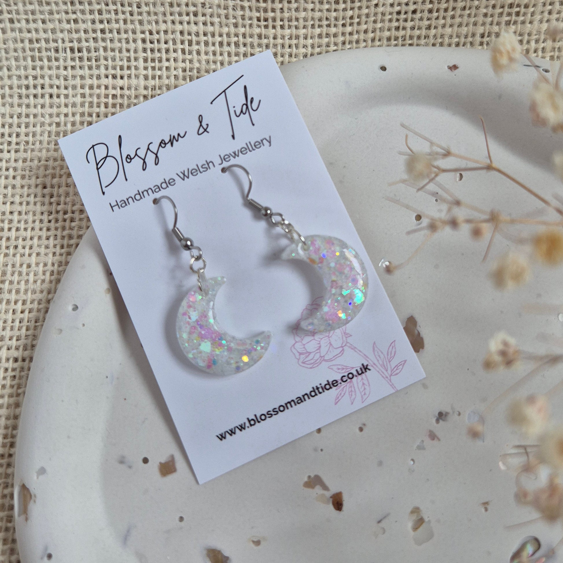 Half moon shaped glitter earrings with opalescent shimmer on silver hooks.