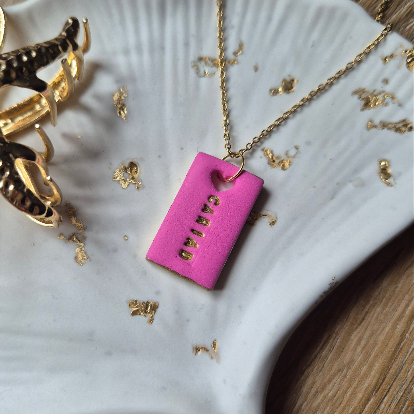 Pink Welsh love necklace displayed on a gold chain, handmade in Wales
