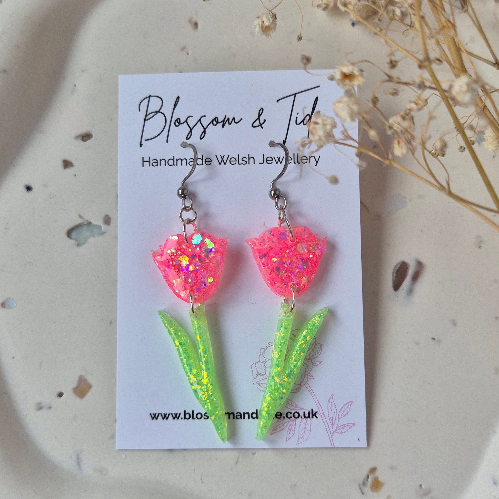 Floral glitter earrings displayed on branded jewellery card.