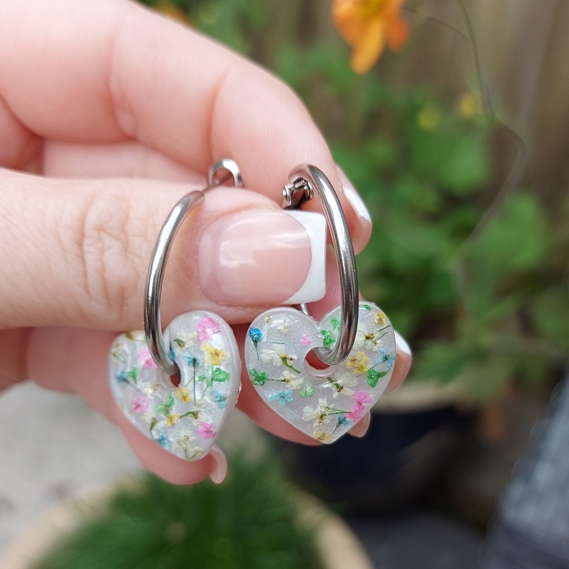 Heart-shaped hoop earrings with multicoloured flowers on a pearly background
