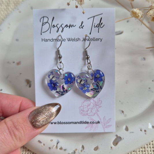 Heart shaped earrings with real pressed forget-me-nots and blue butterflies on stainless steel hook. Presented on a branded Blossom & Tide card.