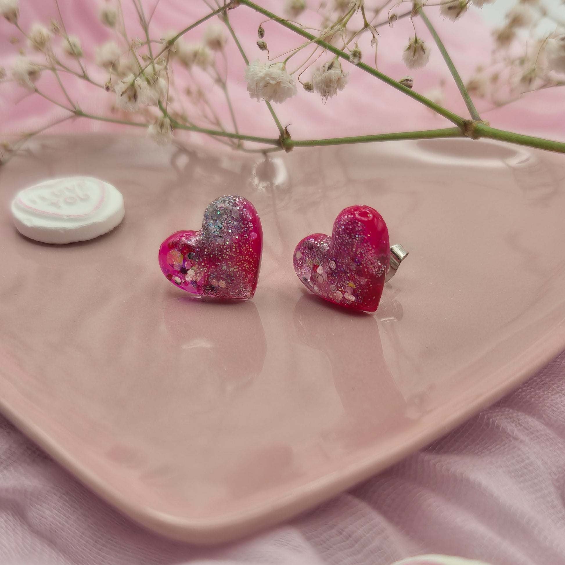 Sparkling red and pink heart earrings with glitter highlights.