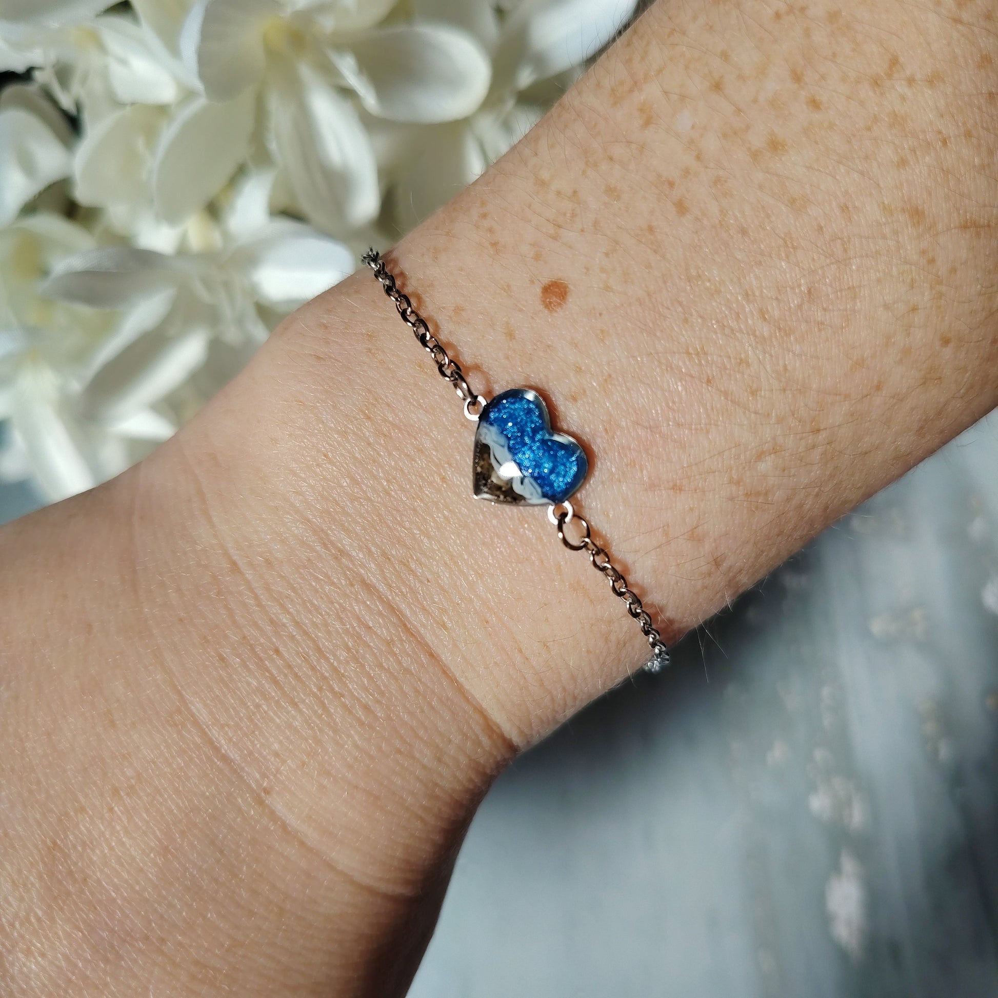 Bracelet with a sand and blue sea on a wrist against a blurred floral background