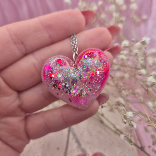 Heart-shaped resin necklace with red, pink, and glitter accents.