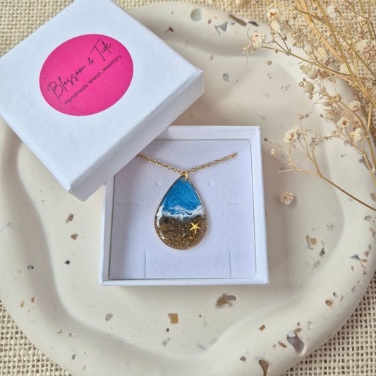 Teardrop pendant necklace made with real Welsh sand and ocean blue resin.