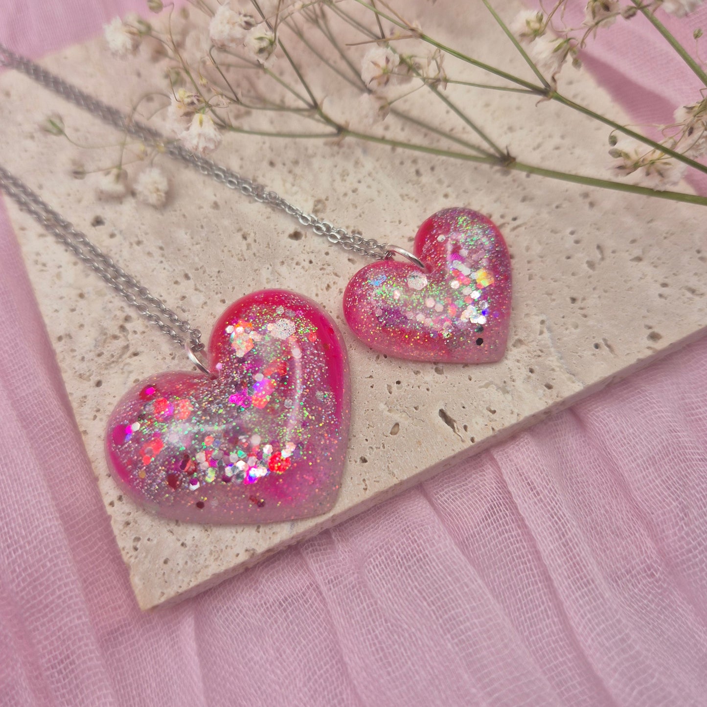 Heart-shaped resin necklace with red, pink, and glitter accents.