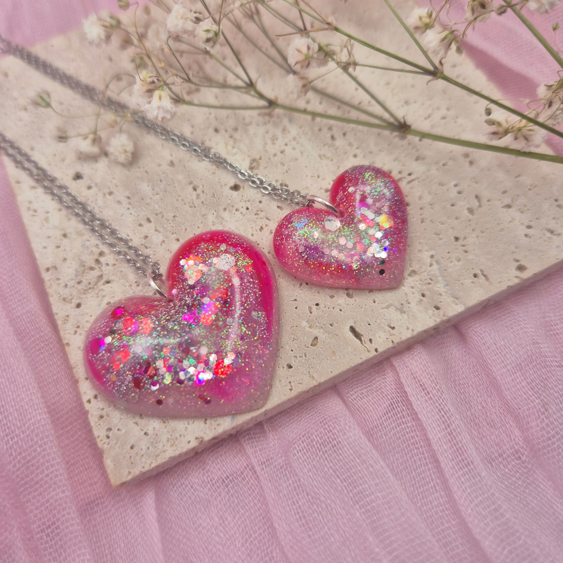 Heart-shaped resin necklace with red, pink, and glitter accents.
