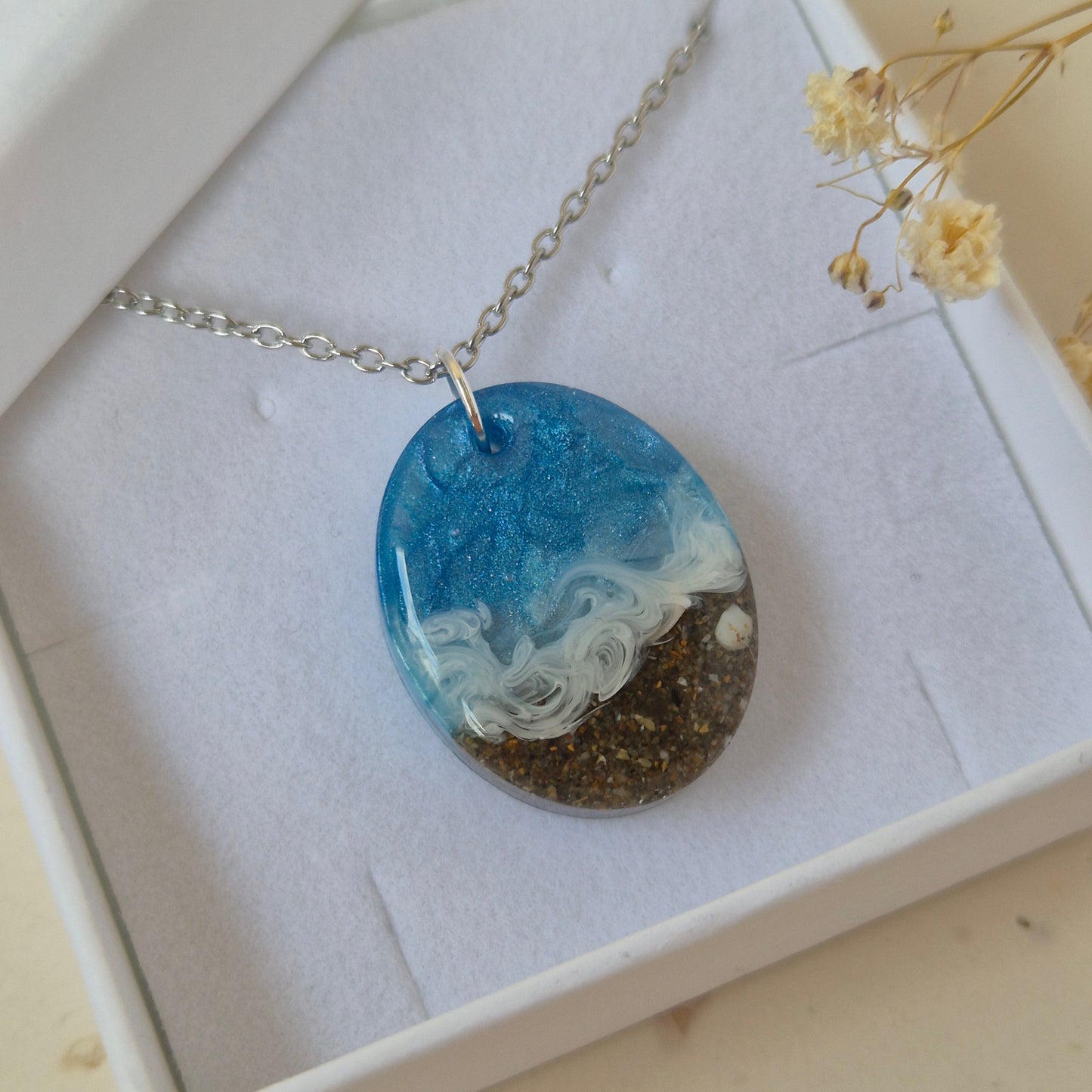 Necklace with a oval pendant featuring beach design in a box