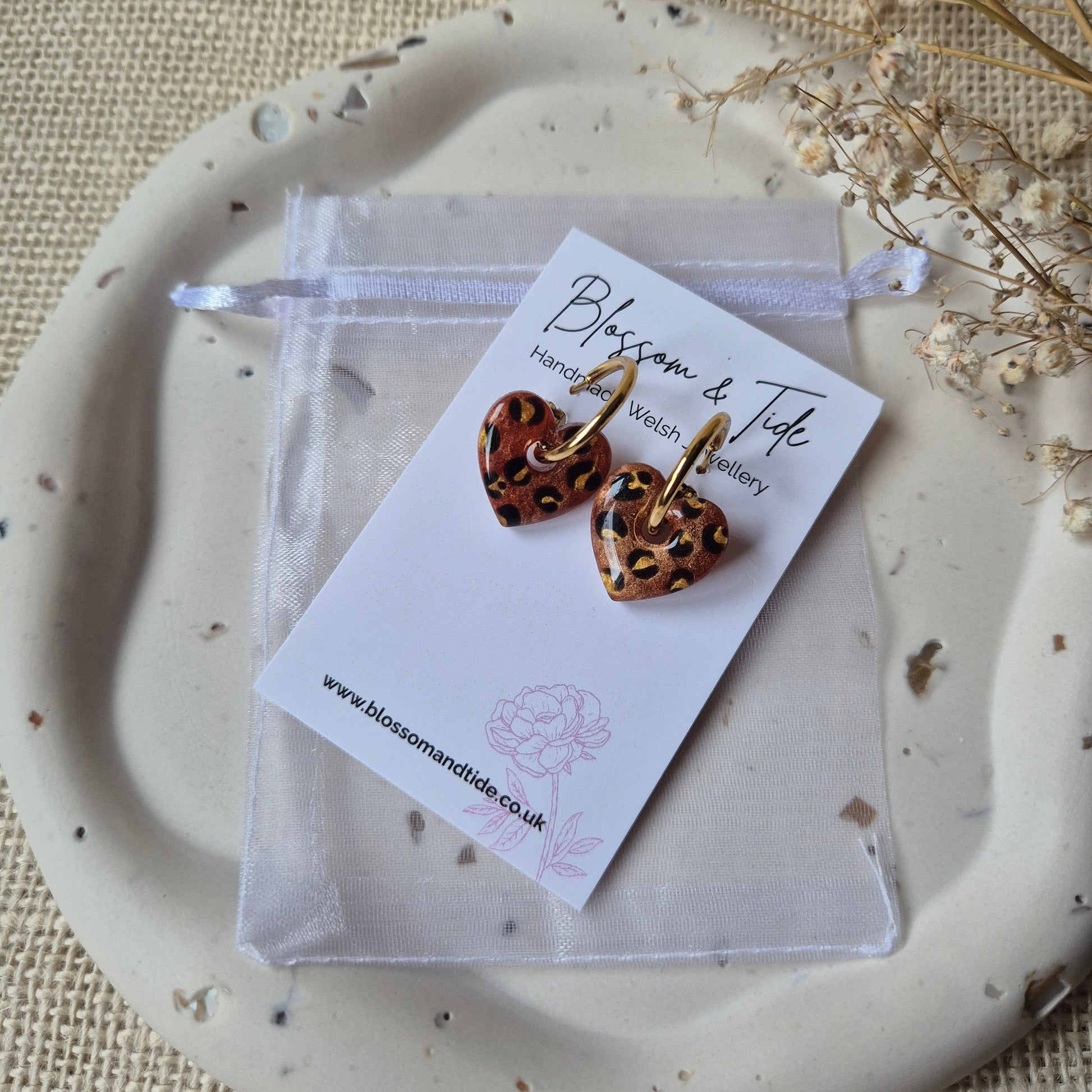 Bronze leopard print earrings on a blossom and tide card against a neutral background