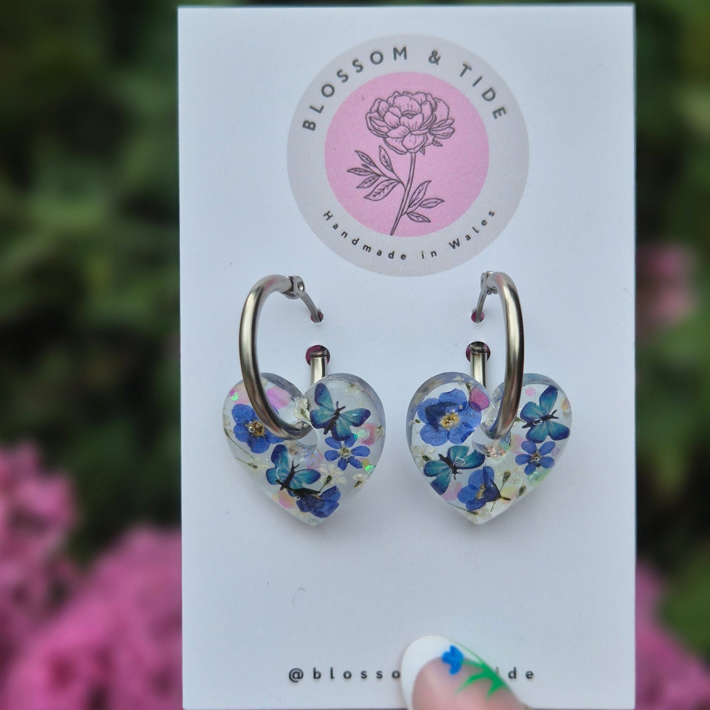 handmade resin earrings, heart shaped with real pressed forget-me-not flowers and blue butterflies. On stainless steel hoops.