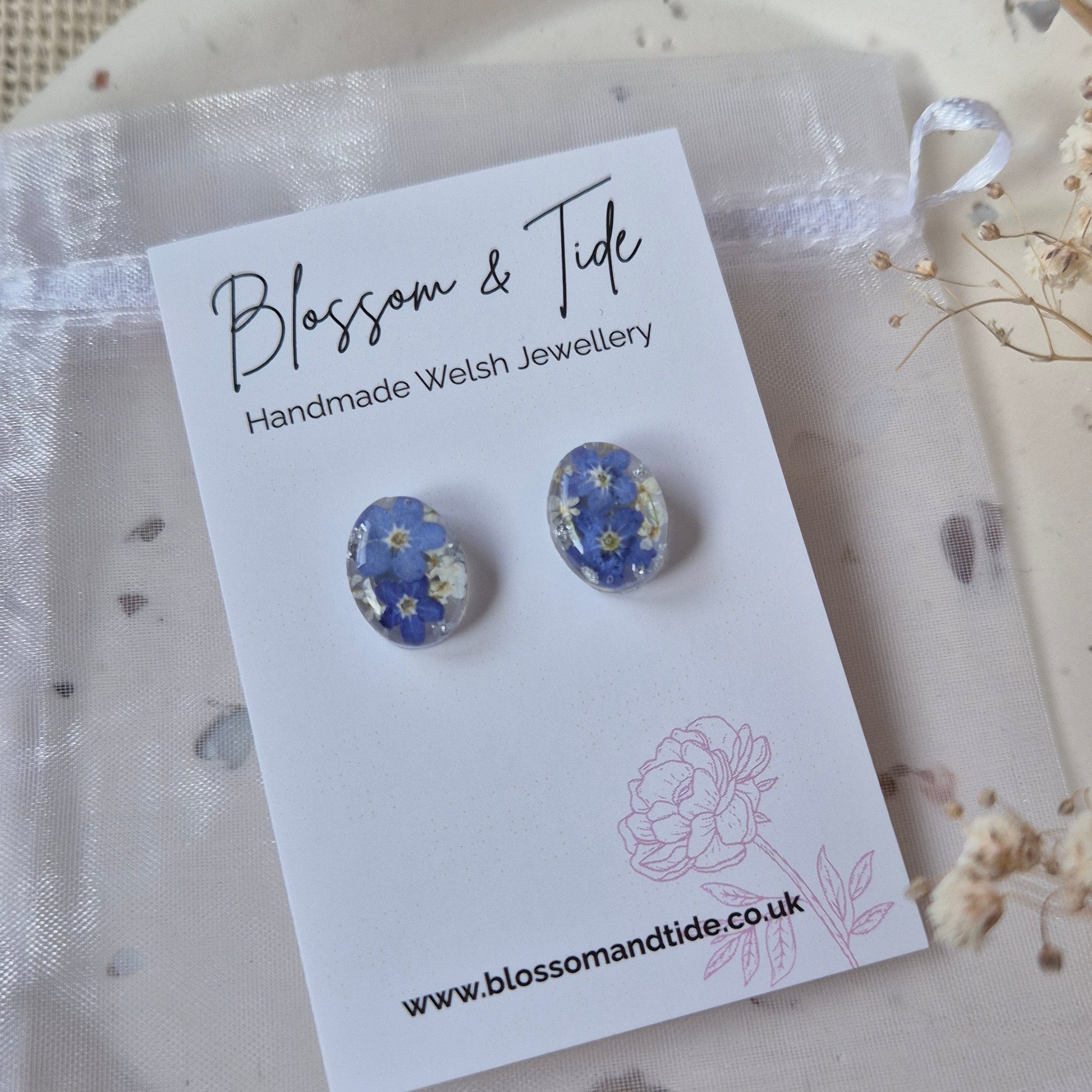 Pair of floral earrings on a 'Blossom & Tide' branded card.
