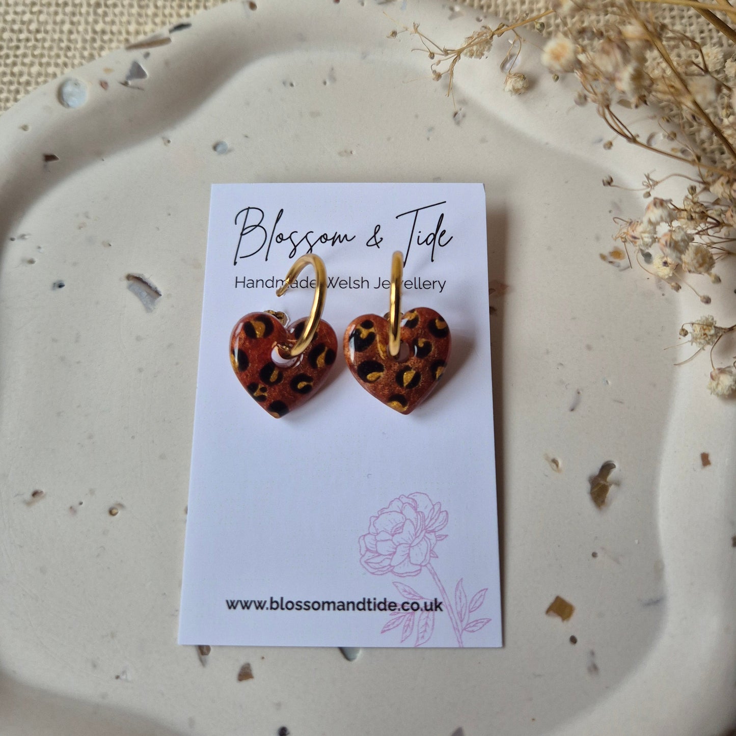 Brown and gold leopard print earrings on a blossom and tide card against a neutral background