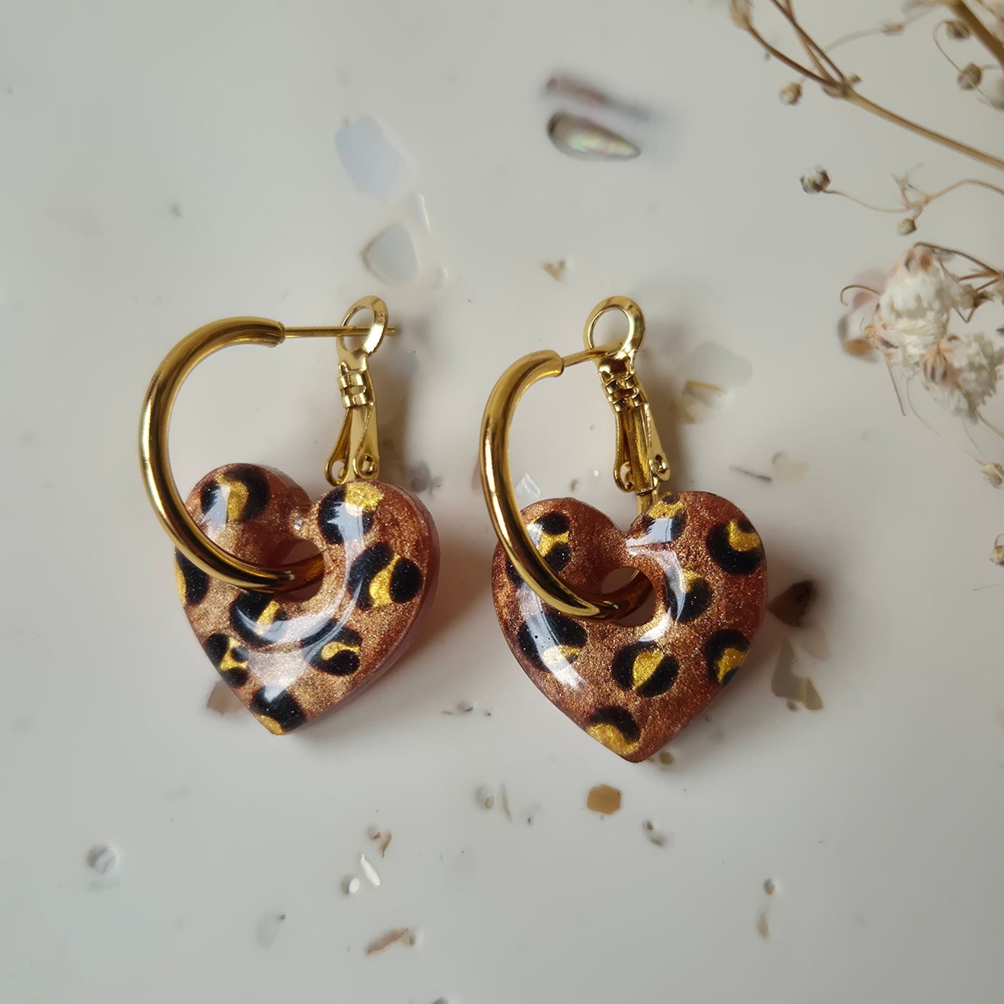 Bronze leopard print earrings on gold hoops against a neutral background