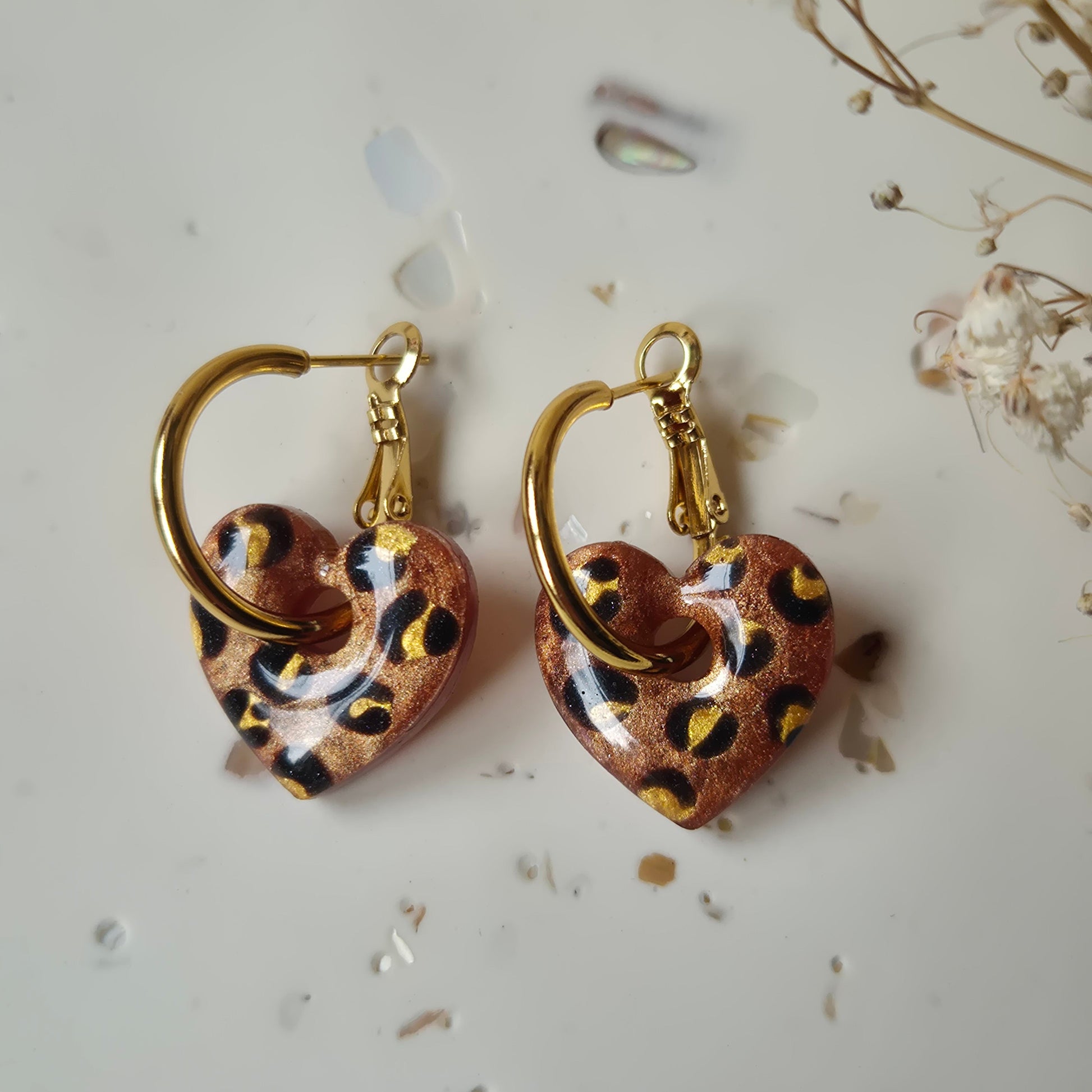 Bronze leopard print earrings on gold hoops against a neutral background